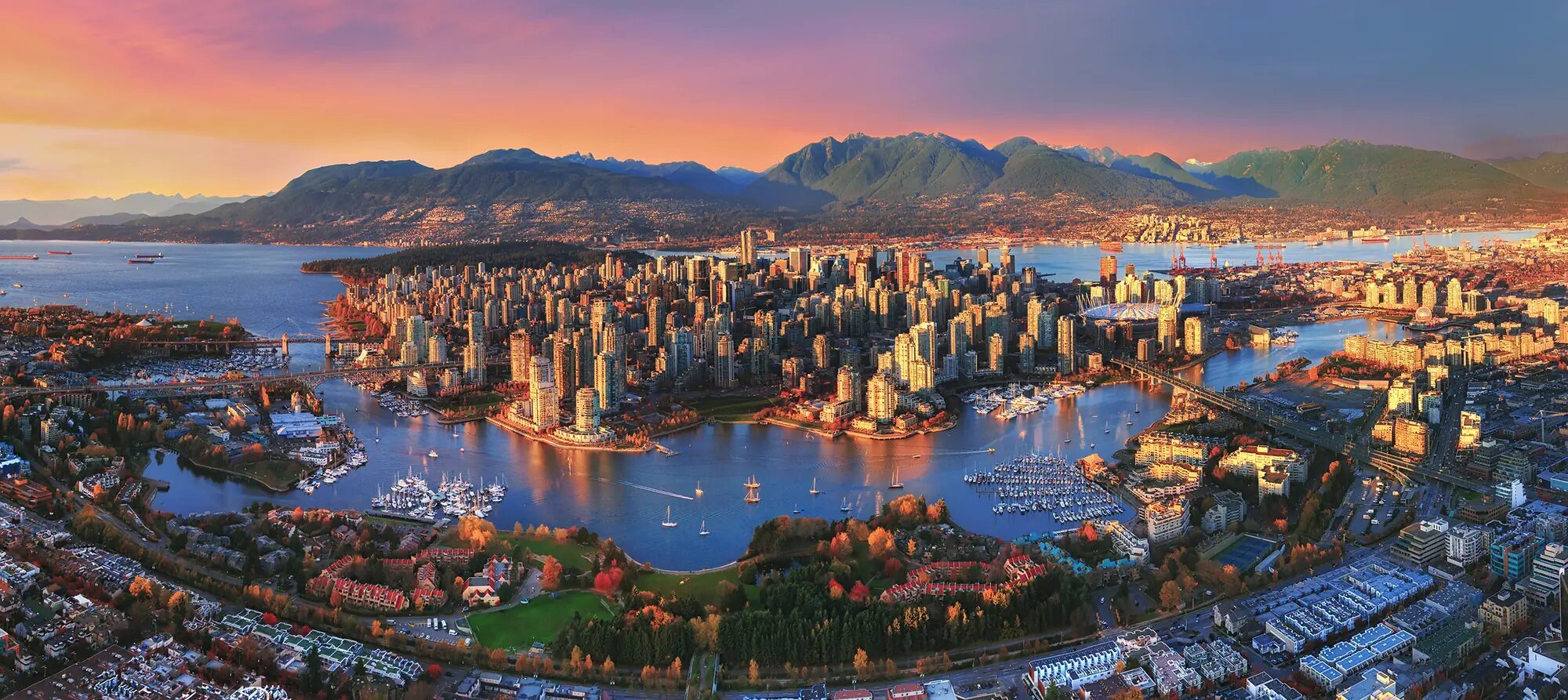 Aerial sunset view of downtown Vancouver, False Creek, and the North Shore mountains